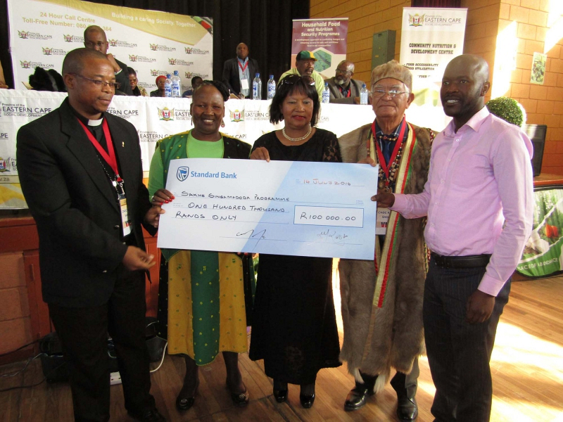 Rev Siyabonga Tambo (left) and Thanduxolo Buka (right) from Sakhe Singamadoda receive their cheque from Social Development MEC Nancy Sihlwayi, Kouga Executive Mayor Daphne Kettledas and Chief Michael Williams.